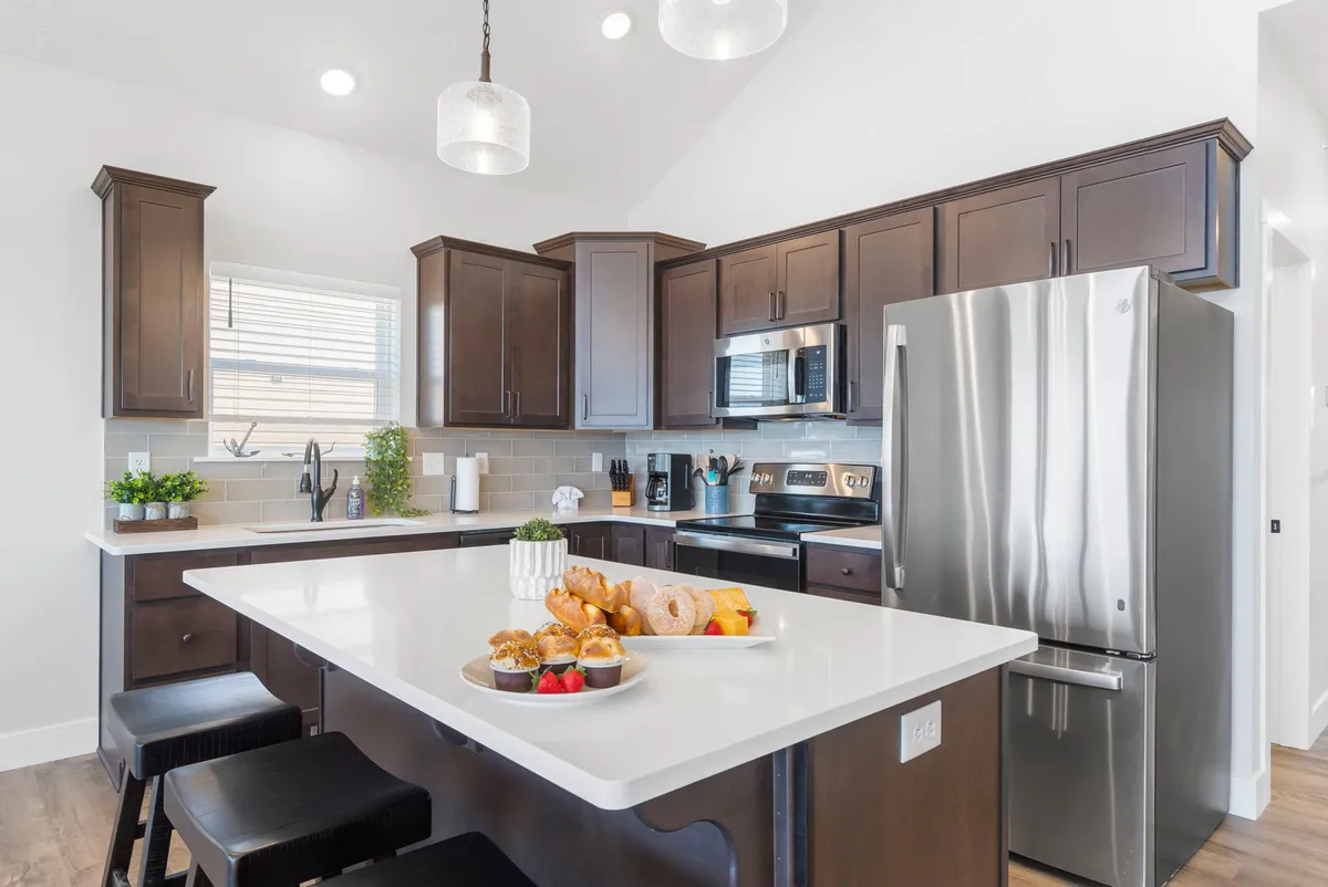 A modern kitchen island with a food display, stainless steel appliances, and warm lighting. The scene is ready for meal preparation, casual family dining, or hosting festive celebrations.
