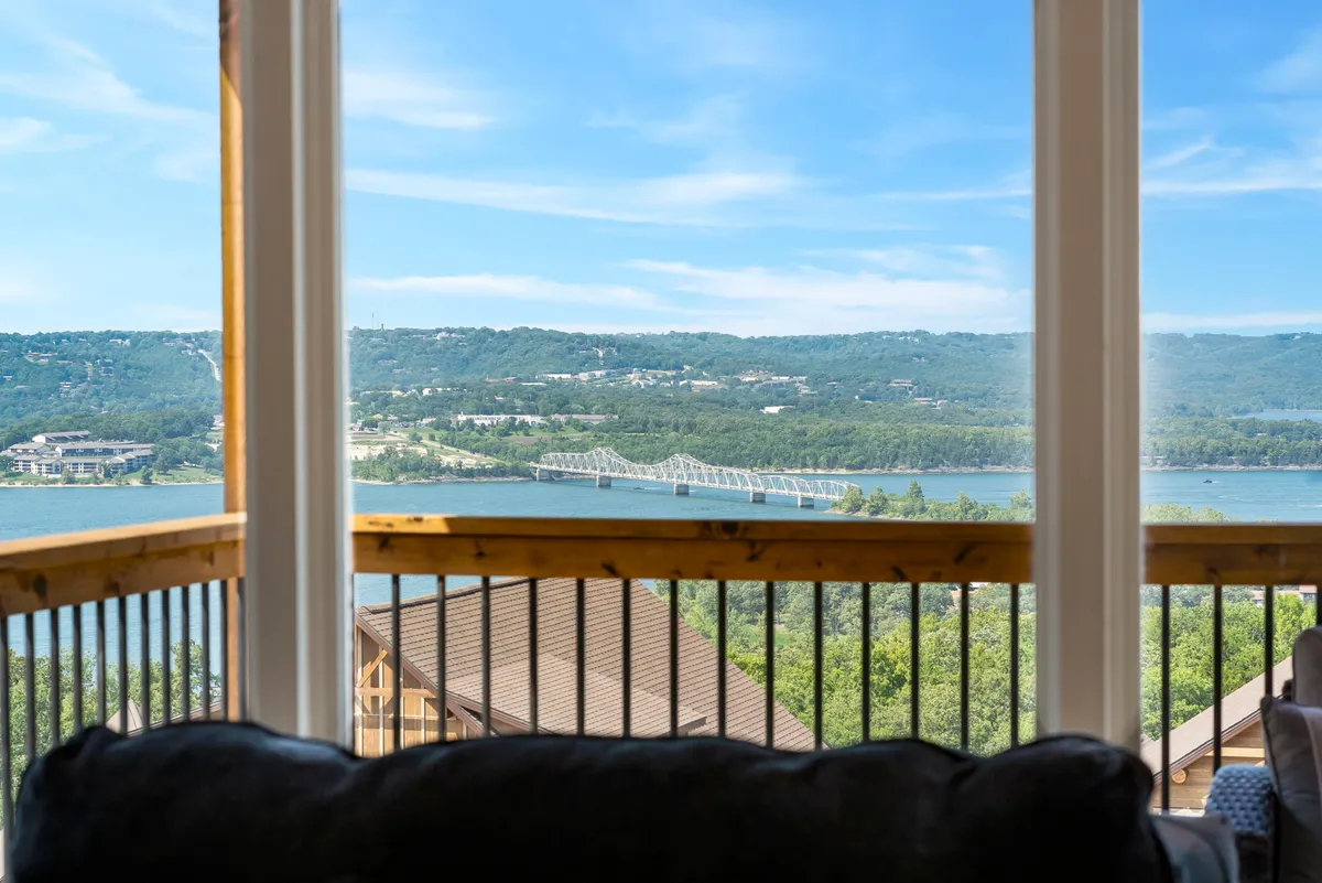 A broad scenic view of the lake, with a wooden bridge stretching across the water and rolling hills in the background. The tranquil ambiance invites exploration, relaxation, and connection with the natural beauty of the Ozarks.